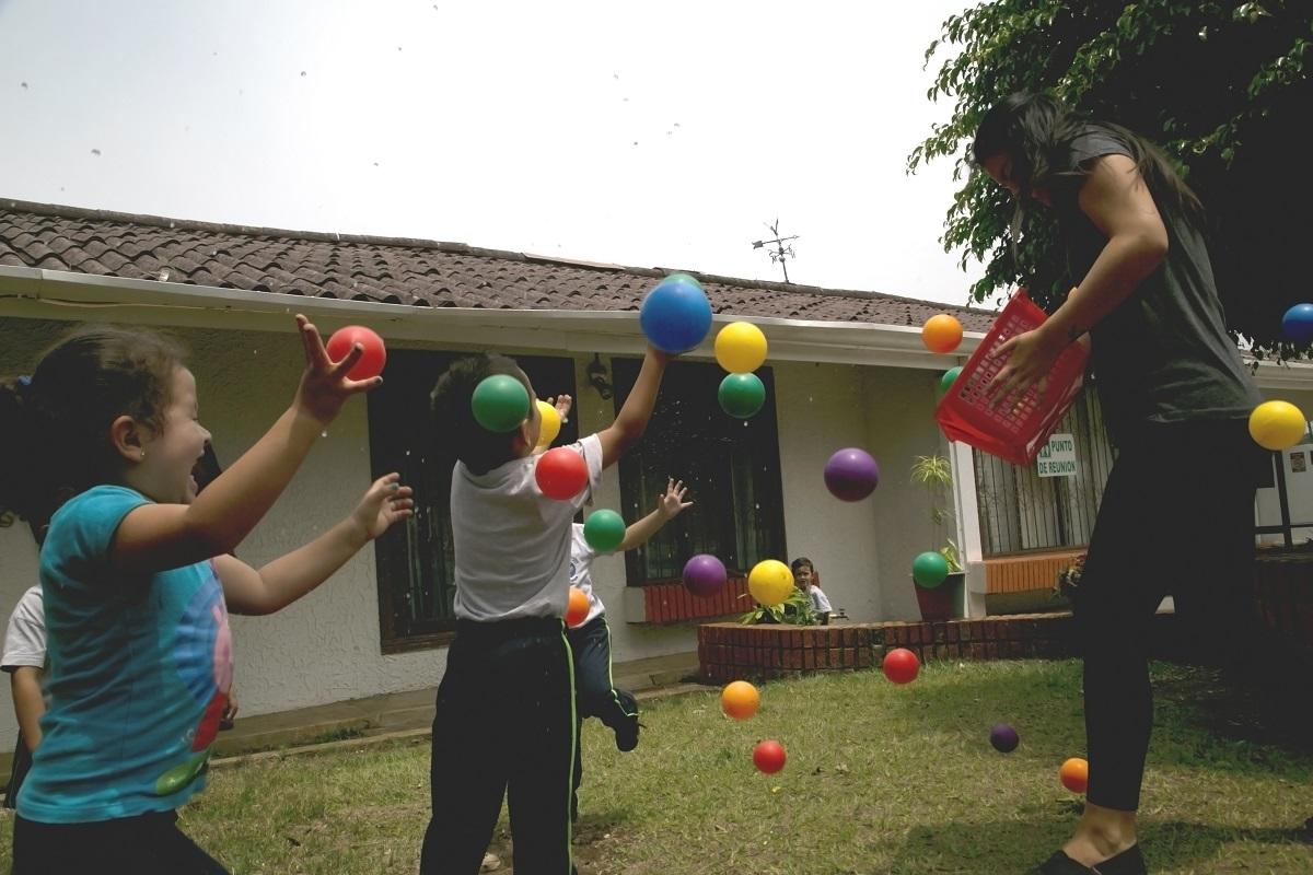 A Projects Abroad volunteer with children in Costa Rica play with balls outside Volunteers and the children play with colourful balls as part of their Childcare volunteer work in Costa Rica